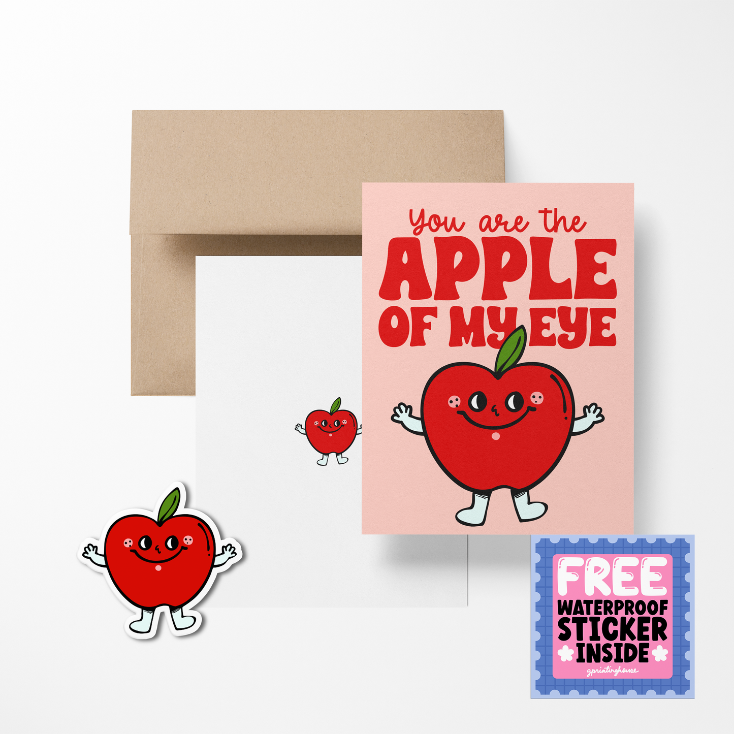 A greeting card with a illustration of a red apple with facial features and arms, accompanied by the phrase 'You are the APPLE of my EYE'. There is also a brown envelope and a free waterproof vinyl sticker included.