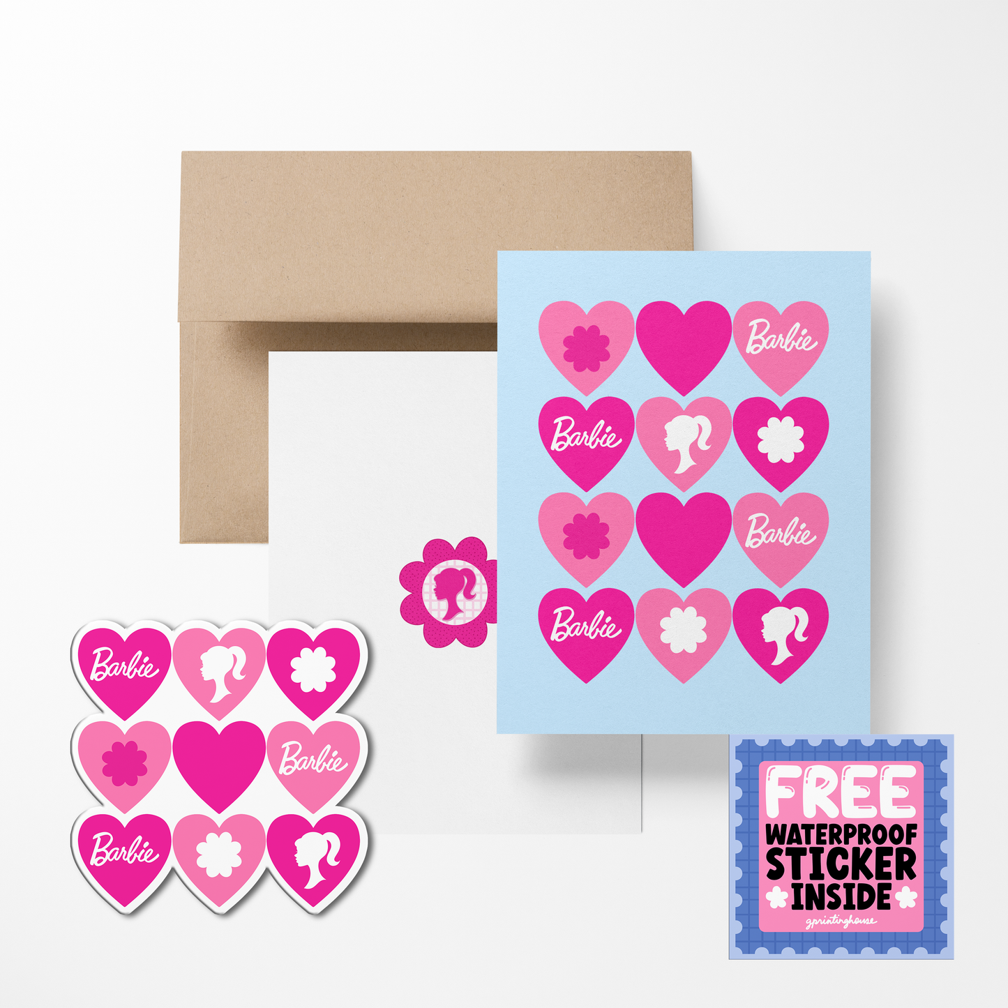 A greeting card with pink hearts and Barbie logos, accompanied by a brown envelope and a free waterproof vinyl sticker.