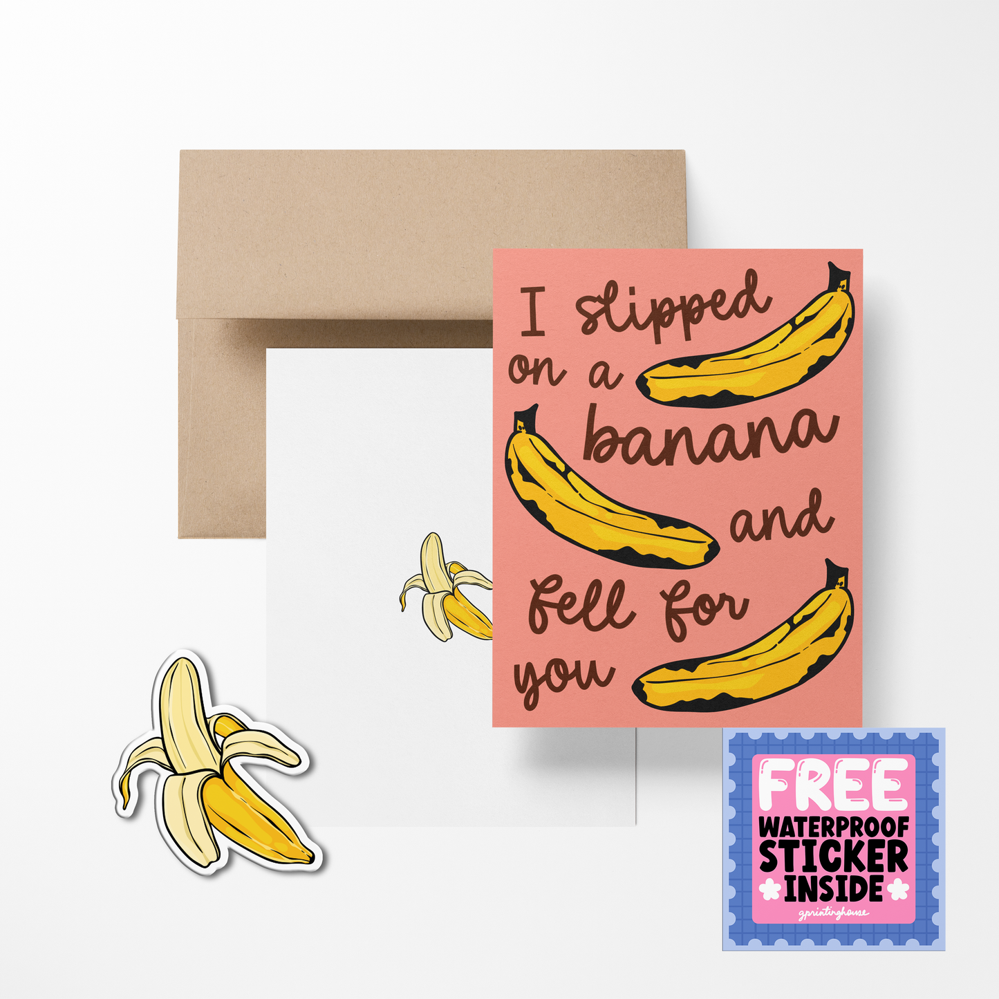 A greeting card with a pink background featuring illustrations of bananas and the phrase 'I slipped on a banana and fell for you'. There is also a free waterproof vinyl sticker included, depicted as a banana split.