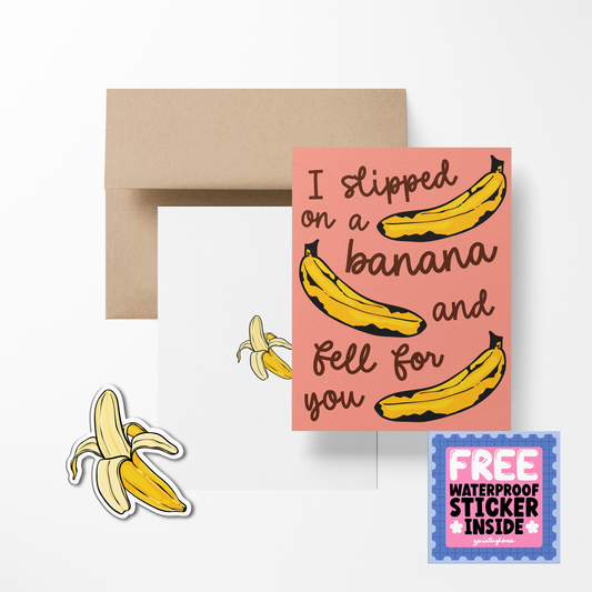 A greeting card with a pink background featuring illustrations of bananas and the phrase 'I slipped on a banana and fell for you'. There is also a free waterproof vinyl sticker included, depicted as a banana split.