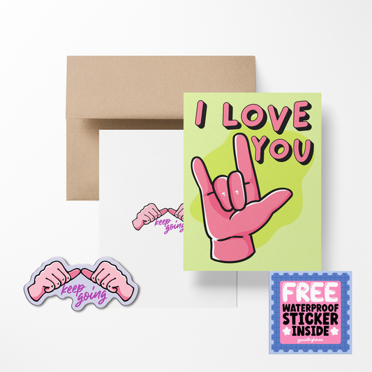 A greeting card with 'I LOVE YOU' text and a heart symbol, accompanied by a sticker with the text 'Keep Going'. There is also a brown envelope in the background.
