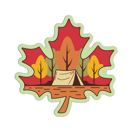 A die-cut sticker or decal shaped like a maple leaf, featuring a camping scene with a beige tent, autumn trees in red, orange, yellow, and green, and a brown ground layer, shown on a plain white background.