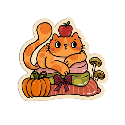 A die-cut cartoon sticker featuring an orange cat curled up on stacked pink, green, and red items, with a pumpkin, mushrooms, and a red apple, shown on a plain white background.