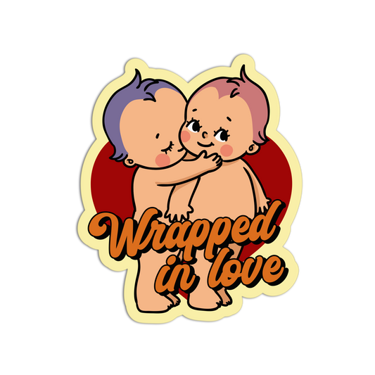 Sticker with two cartoon babies hugging and 'Wrapped in Love' text on a white background