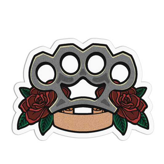 A die-cut vinyl sticker featuring a metallic brass knuckle design with red roses and green leaves on a white background.